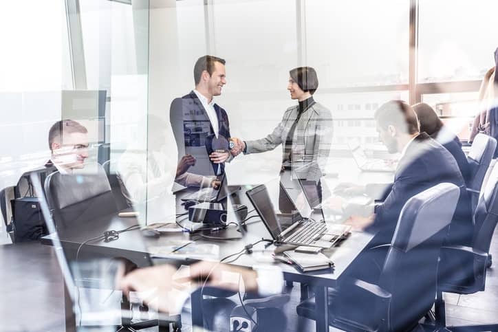 Business professionals collaborating and shaking hands in a modern office.